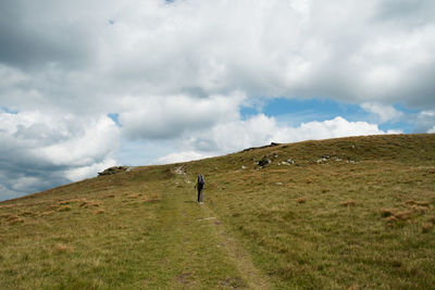 Man walking on field against sky