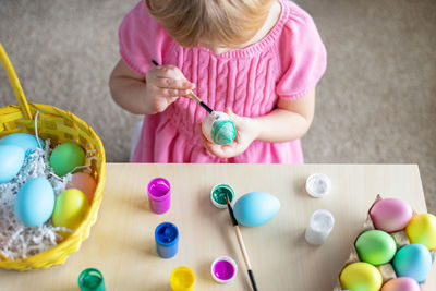 Little girl in easter bunny ears painting colored eggs. eastercelebration at home and craft concept.