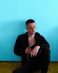 Young man looking away while sitting on wall at home