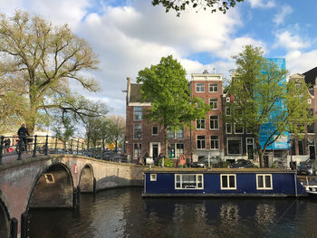 Bridge over canal by buildings in city against sky