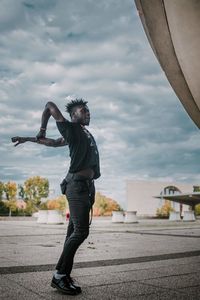 Side view of man dancing on footpath against sky