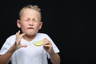 Portrait of man holding ice cream against black background