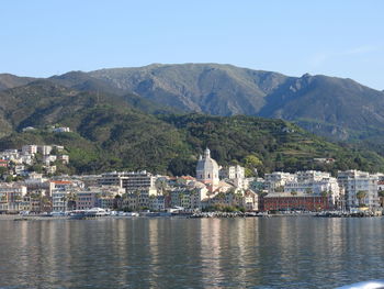 Buildings by sea against mountain