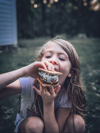 Portrait of young woman eating a s'mores snack outside