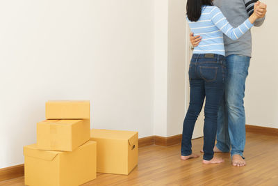 Rear view of people standing on hardwood floor against wall