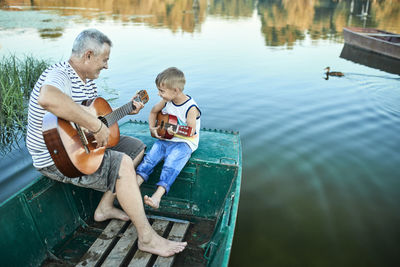 Grandfather teaching grandson playing guitar