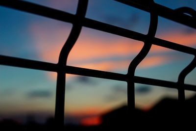 Silhouette fence against sky during sunset