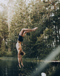 Full length of shirtless man in lake against trees in forest