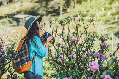 Side view of woman standing by flowering plants