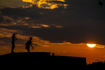 Silhouette people standing against sky during sunset