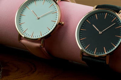 Close-up of wristwatches on pink rolled paper at table