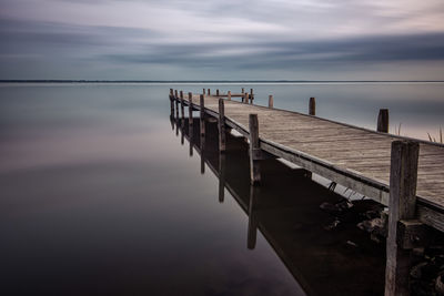 Pier on sea against sky during sunset