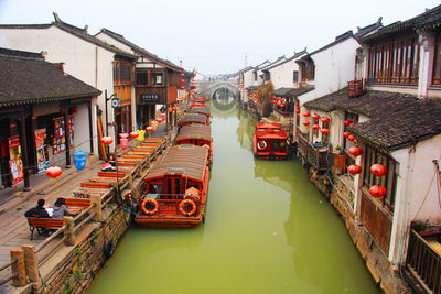 High angle view of houseboats moored on canal amidst houses