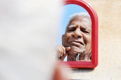 Reflection of senior man shaving outdoors