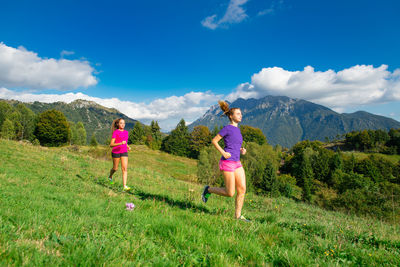 Full length of girl running on grass against sky