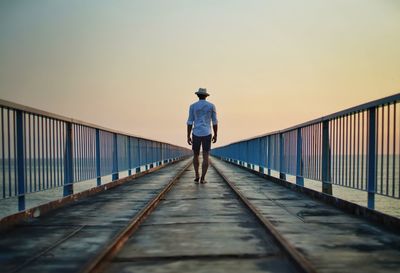 Rear view of man walking on footbridge