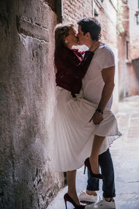 Side view of young couple kissing against wall