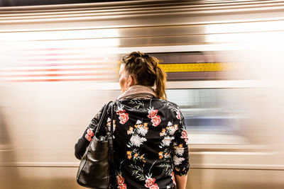 Rear view of woman standing by train at subway station