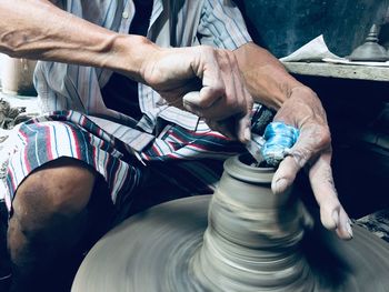 Midsection of man molding shape on pottery wheel