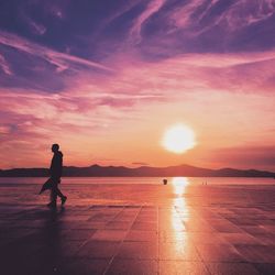 Silhouette woman on beach against sky during sunset