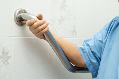 Close-up of man holding hands against white wall