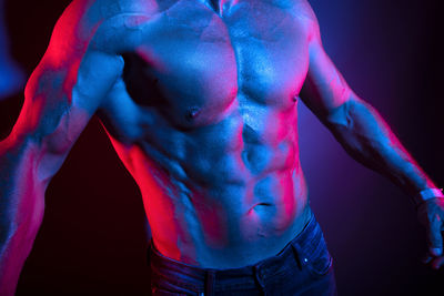 Close-up of shirtless man against black background