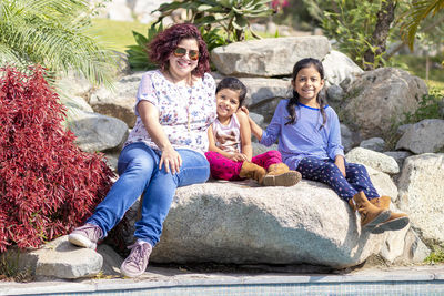 Smiling family sitting on rock at park