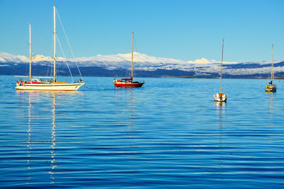 Boats on lake against snowcapped mountains