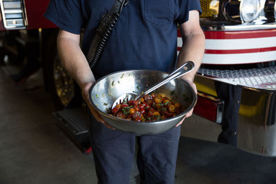 Midsection of man holding cherry tomatoes container