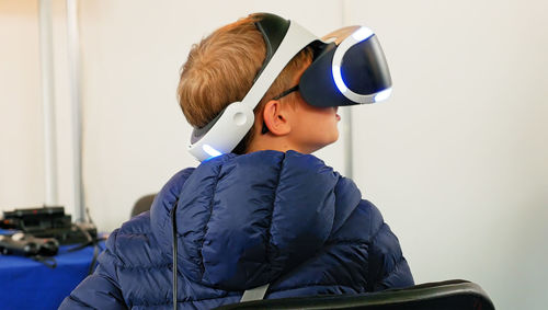 Rear view of boy using virtual reality simulator