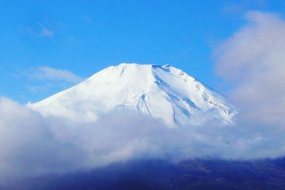 Scenic view of snow covered mountains against blue sky