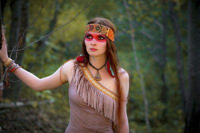 Young woman in traditional clothing looking away while standing in forest