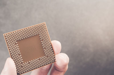 Cropped hand of person holding microprocessor over table