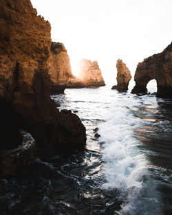 Scenic view of sea by rock formation against sky