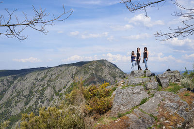 Women standing on rock against sky