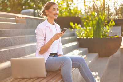 Young woman using mobile phone while sitting on seat