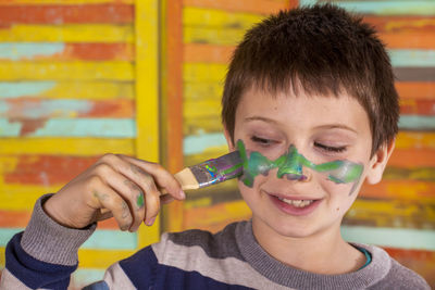 Boy painting his face with brush.