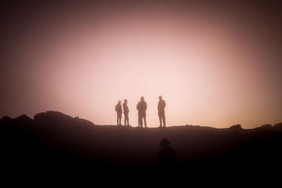 Silhouette people standing on mountain against sky during sunset