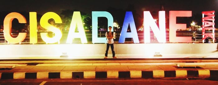 Blurred motion of woman standing on illuminated city at night