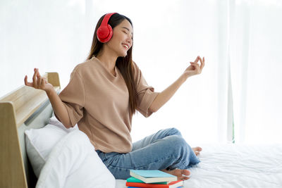 Side view of young woman sitting on bed