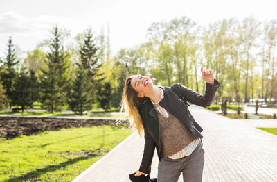 Woman standing by road against trees