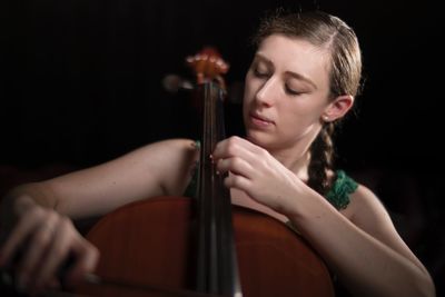 Woman playing violin against black background