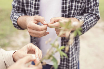 Midsection of couple removing seeds from plant at organic farm