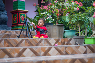 Full length of cute baby girl sitting on potted plant