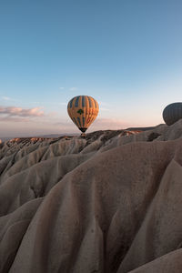 Hot air balloon flying over rocks against sky