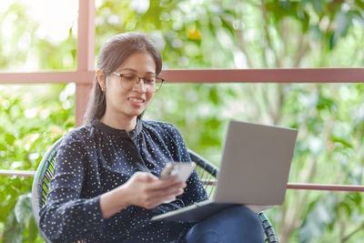 Young woman using mobile phone while sitting on camera