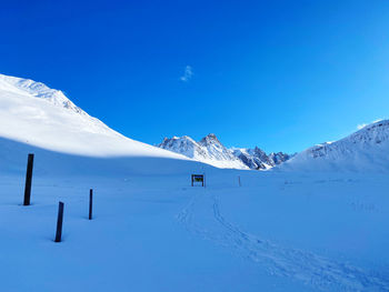 Scenic view of snow covered mountains against blue sky