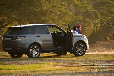 Couple standing by car on field