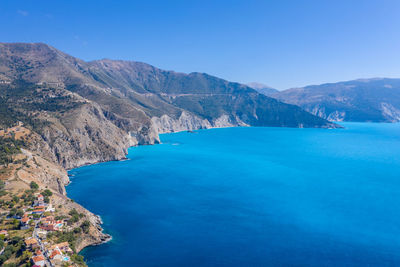 Scenic view of sea and mountains against clear blue sky