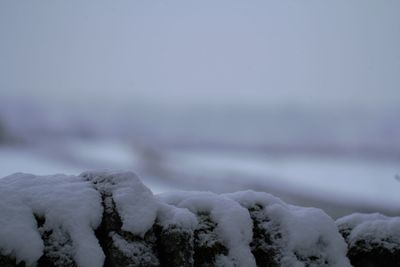 Close-up of snow on field against sky